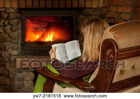 Stock Photo - Woman reading a book in front of chimney.. Fotosearch