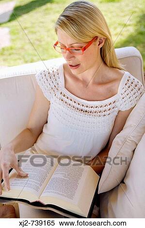 Stock Photography - Woman reading a book in the terrace. Fotosearch