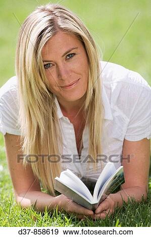 Woman reading a book laying on the grass View Large Photo Image Stock Photo - Woman reading a book laying on the grass. Fotosearch