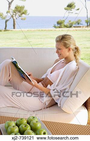 Woman reading a magazine at home outdoors View Large Photo Image Stock Image - Woman reading a magazine at home outdoors. Fotosearch