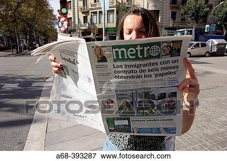 Stock Photo - Woman reading Metro free newspaper in Barcelona. Spain. Fotosearch