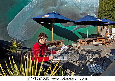 Woman reading morning newspaper, Sperm whales mural on cafe wall, Kaikoura, North Canterbury, South Island, New Zealand View Large Photo Image Stock Photography - Woman reading morning newspaper, Sperm whales mural on cafe wall, Kaikoura, North Canterbury, South Island, New Zealand. Fotosearch