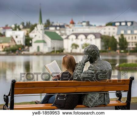 Stock Image - Woman reading next to statue of an Icelandic poet, Tomas Gudmundsson, Reykjavik, Iceland The city of Reykjavik has been designated as a UNESCO city of literature. Fotosearch