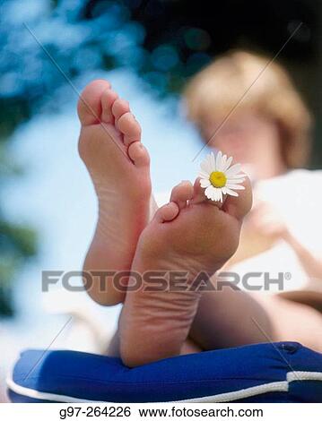 Stock Photograph - Woman reading with a flower on feet. Fotosearch