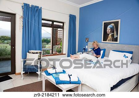 Woman relaxes with a brochure on a white bed at a guesthouse, Victoria Bay, Garden Route, Western Cape, South Africa. View Large Photo Image Stock Image - Woman relaxes with a brochure on a white bed at a guesthouse, Victoria Bay, Garden Route, Western Cape, South Africa.. Fotosearch