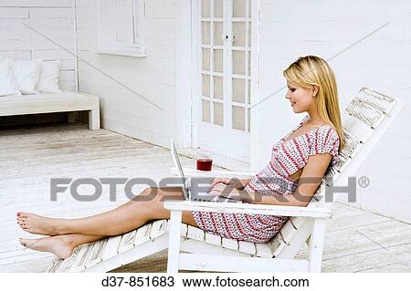 Woman relaxing at home with her laptop View Large Photo Image Stock Image - Woman relaxing at home with her laptop. Fotosearch