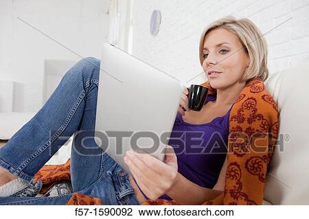 Woman relaxing on her bed with her tablet computer View Large Photo Image Stock Image - Woman relaxing on her bed with her tablet computer. Fotosearch