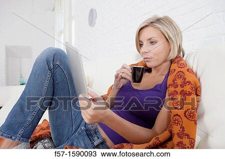 Woman relaxing on her bed with her tablet computer View Large Photo Image Stock Image - Woman relaxing on her bed with her tablet computer. Fotosearch