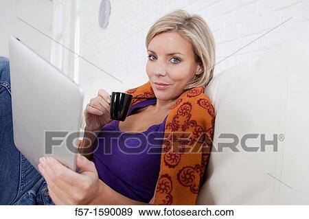 Woman relaxing on her bed with her tablet computer View Large Photo Image Stock Photo - Woman relaxing on her bed with her tablet computer. Fotosearch