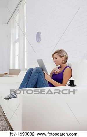 Woman relaxing on her sofa with her tablet computer View Large Photo Image Stock Image - Woman relaxing on her sofa with her tablet computer. Fotosearch