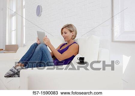 Woman relaxing on her sofa with her tablet computer View Large Photo Image Stock Image - Woman relaxing on her sofa with her tablet computer. Fotosearch
