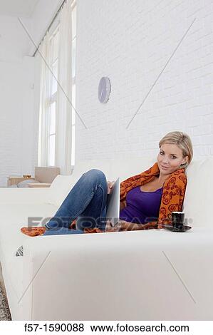 Stock Photo - Woman relaxing on her sofa with her tablet computer. Fotosearch