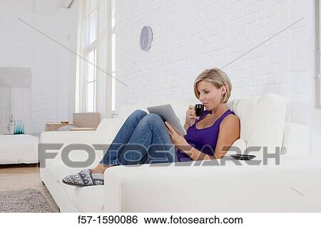 Woman relaxing on her sofa with her tablet computer View Large Photo Image Stock Photograph - Woman relaxing on her sofa with her tablet computer. Fotosearch