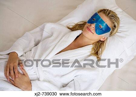 Stock Image - Woman relaxing with eye mask. Fotosearch