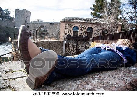 Stock Photograph - Woman resting by the Tagus river, Toledo, Spain.. Fotosearch