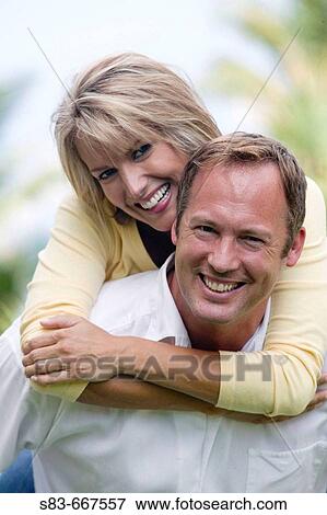 Woman riding on mans back smilling at camera View Large Photo Image Stock Photo - Woman riding on mans back smilling at camera. Fotosearch
