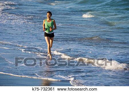 Woman running along surf with weights in hand View Large Photo Image Stock Image - Woman running along surf with weights in hand. Fotosearch