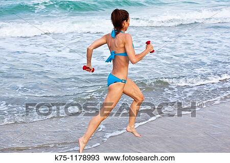 Stock Image - woman running on beach. Fotosearch
