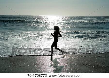 Stock Image - Woman running on Punta de Tralca beach, Chile.. Fotosearch