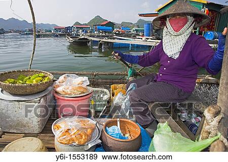 Woman selling bread doughnuts fruit and drinks rows her shop around floating fishing village Cat Ba Town bay north east Vietnam View Large Photo Image Stock Photo - Woman selling bread doughnuts fruit and drinks rows her shop around floating fishing village Cat Ba Town bay north east Vietnam. Fotosearch