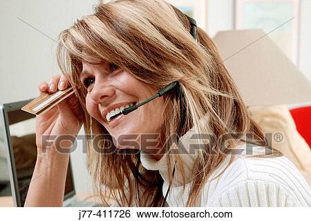 Stock Photograph - Woman shopping by phone, credit card in hand.. Fotosearch