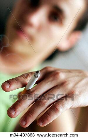 Stock Image - Woman showing a burning cigarette.. Fotosearch