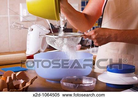 Woman sifting flower into a mixing bowl in the preparation of chocolate cake ingredients View Large Photo Image Stock Photography - Woman sifting flower into a mixing bowl in the preparation of chocolate cake ingredients. Fotosearch