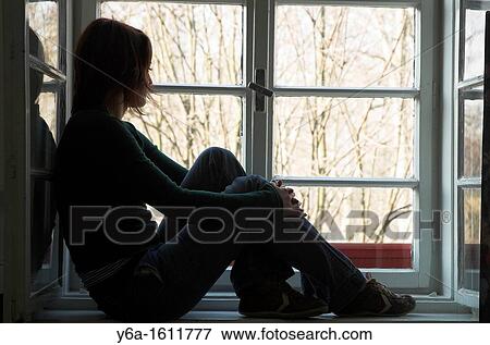 Woman silhouetted sitting on window ledge looking out of window View Large Photo Image Stock Photo - Woman silhouetted sitting on window ledge looking out of window. Fotosearch