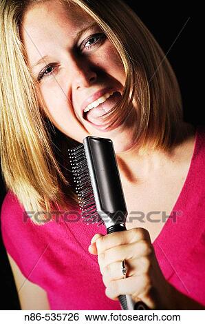 Woman singing into hair brush View Large Photo Image Stock Photograph - Woman singing into hair brush. Fotosearch