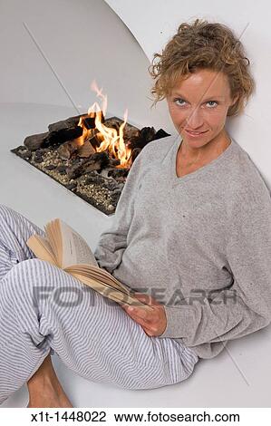 Woman sitting by fireplace, reading View Large Photo Image Stock Image - Woman sitting by fireplace, reading. Fotosearch