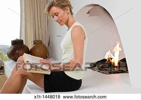 Woman sitting by fireplace, reading View Large Photo Image Stock Photo - Woman sitting by fireplace, reading. Fotosearch