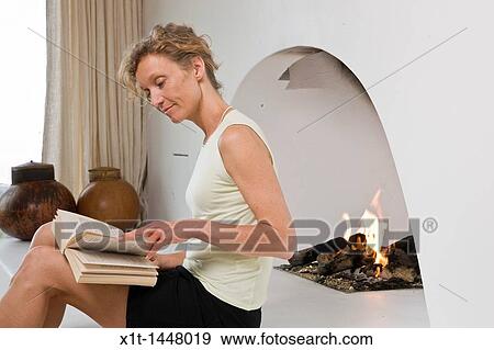 Woman sitting by fireplace, reading View Large Photo Image Stock Photo - Woman sitting by fireplace, reading. Fotosearch