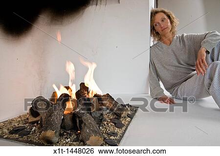 Woman sitting by fireplace View Large Photo Image Stock Photograph - Woman sitting by fireplace. Fotosearch