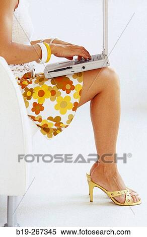Woman sitting down in a chair working with a portable computer View Large Photo Image Stock Photography - Woman sitting down in a chair working with a portable computer. Fotosearch