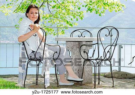 Woman sitting in a patio with sea view View Large Photo Image Stock Photo - Woman sitting in a patio with sea view. Fotosearch
