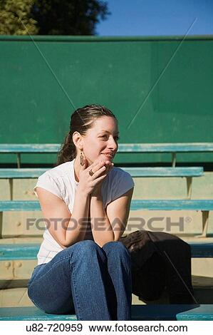 Woman sitting in bleachers at a baseball stadium View Large Photo Image Stock Photo - Woman sitting in bleachers at a baseball stadium. Fotosearch