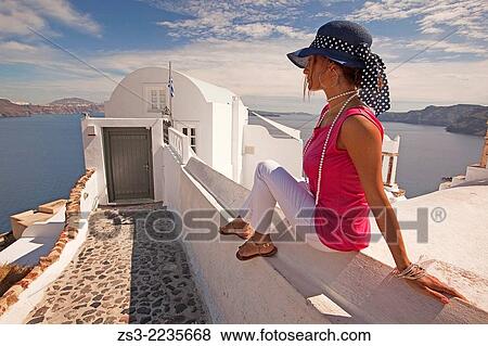 Woman sitting in front of a hotel entrance in Oia town, Santorini, Cyclades Islands, Greek Islands, Greece, Europe. View Large Photo Image Stock Photo - Woman sitting in front of a hotel entrance in Oia town, Santorini, Cyclades Islands, Greek Islands, Greece, Europe.. Fotosearch