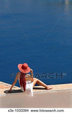 Picture - Woman sitting in front of a sweeping view of the sea in the island of Symi Greece. Fotosearch