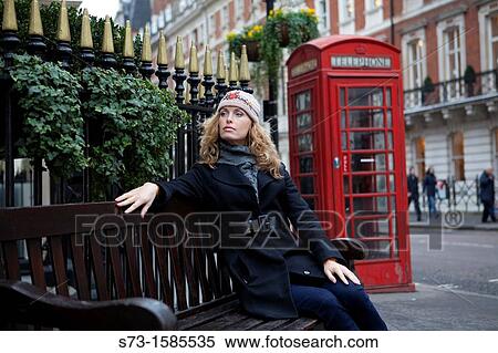 Woman sitting in front of a telephone box in London View Large Photo Image Stock Photography - Woman sitting in front of a telephone box in London. Fotosearch