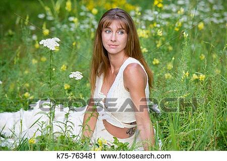 Woman sitting in meadow of wildflowers View Large Photo Image Stock Image - Woman sitting in meadow of wildflowers. Fotosearch
