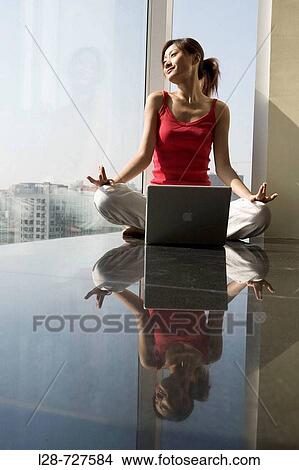 Picture - Woman sitting in yoga position on floor. Fotosearch