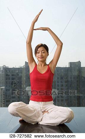 Stock Image - Woman sitting in yoga position on floor. Fotosearch