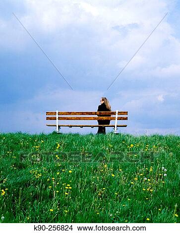 Picture - Woman sitting on bench during upcoming rain. Altes Land, Lower Saxonia. Germany. Fotosearch