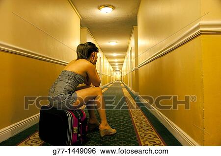 Woman sitting on her bag in hotel aisle View Large Photo Image Stock Photograph - Woman sitting on her bag in hotel aisle. Fotosearch