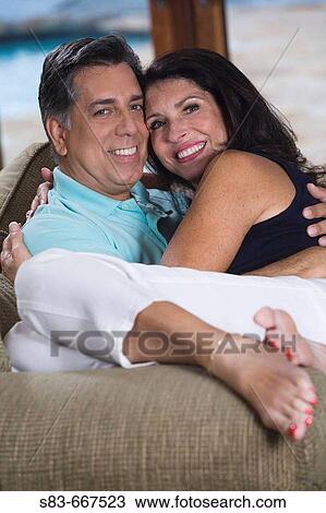 Stock Image - Woman sitting on mans lap on the living room couch. Fotosearch