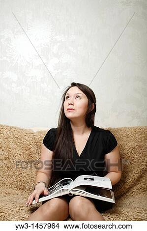 Woman sitting on sofa with book View Large Photo Image Picture - Woman sitting on sofa with book. Fotosearch