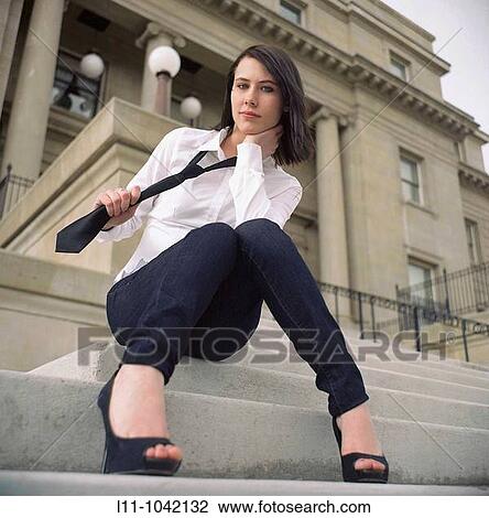 Woman sitting on steps of Public Building pulling on her necktie. View Large Photo Image Stock Image - Woman sitting on steps of Public Building pulling on her necktie.. Fotosearch