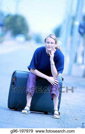 Woman sitting on suitcase View Large Photo Image Stock Photo - Woman sitting on suitcase. Fotosearch