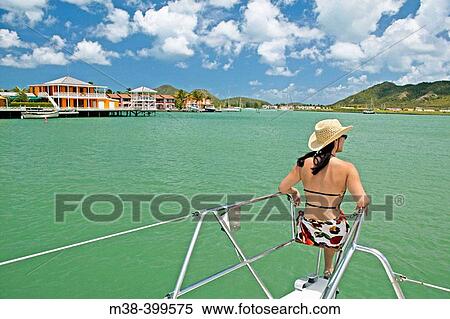 Stock Photography - Woman sitting on the front of a catamaran, sailing in Antigua. Fotosearch