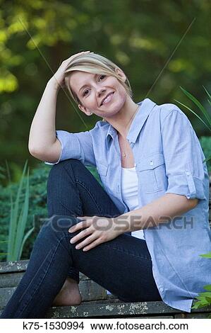Picture - woman sitting outdoors portrait. Fotosearch